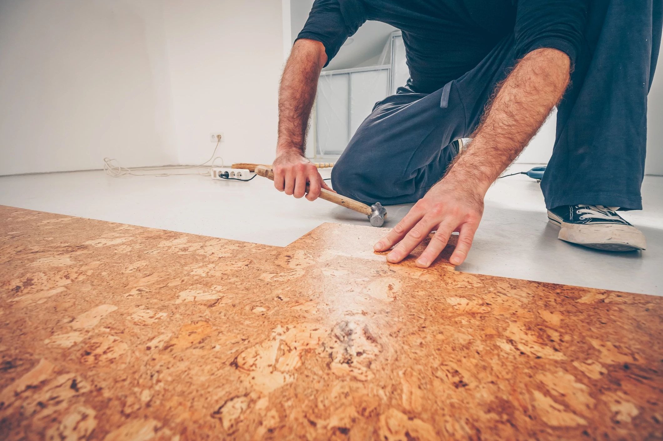 A man is installing cork flooring from Howard Carpenter Floor Covering in Danville KY