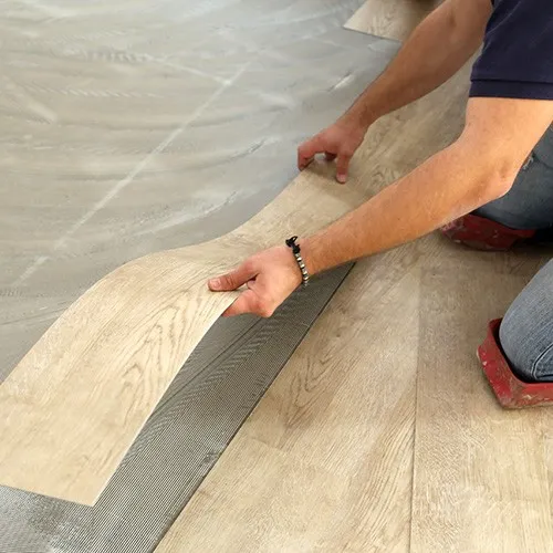 Worker installing vinyl | Howard-Carpenter Floor Covering