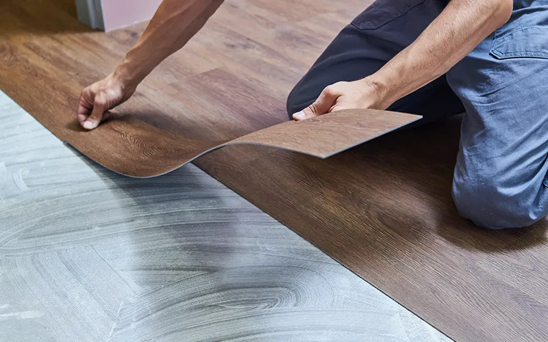 Worker installing luxury vinyl | Howard-Carpenter Floor Covering